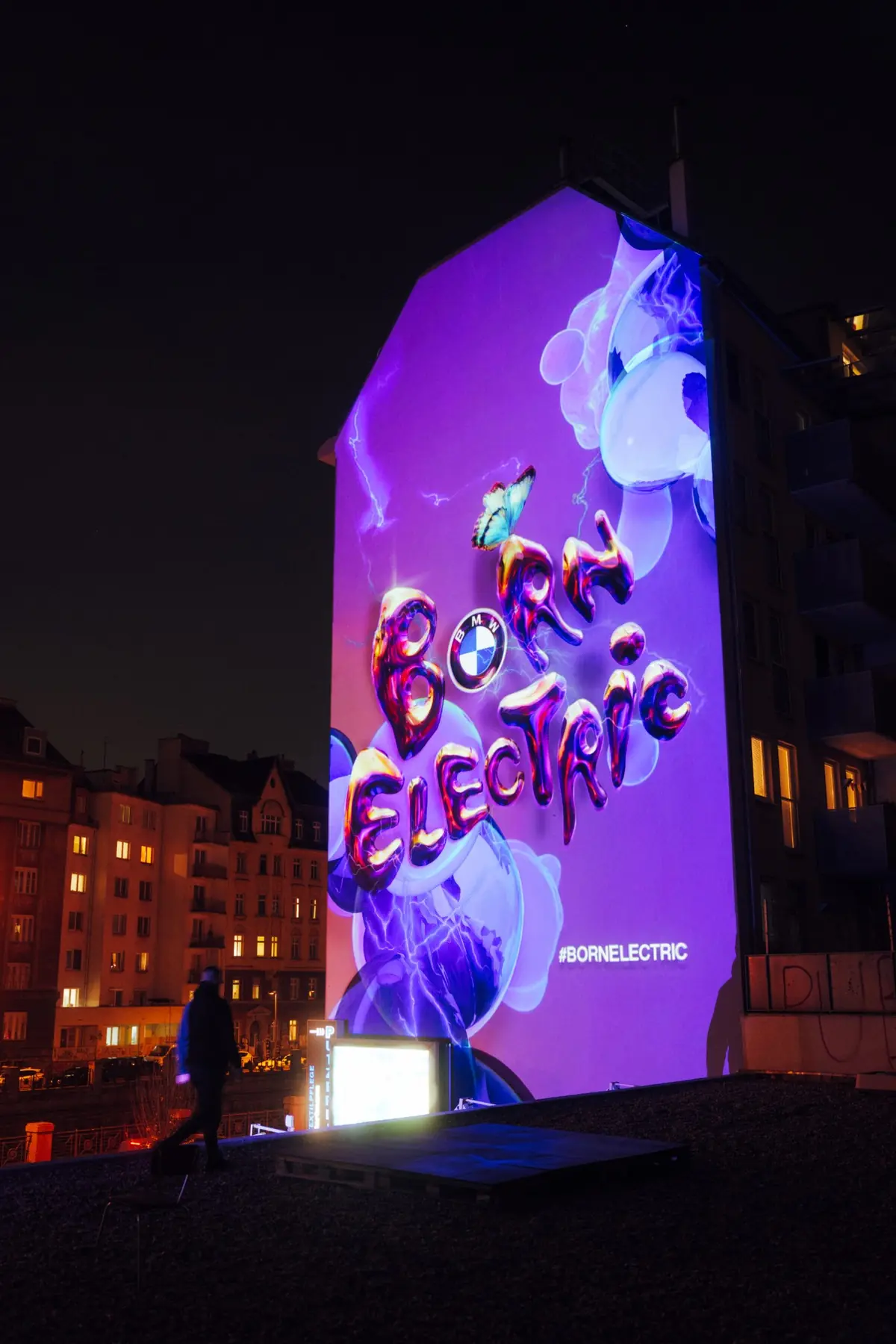 The Born Electric mural on a gable wall in Mariahilf, lit at night